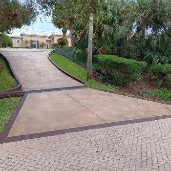 Concrete driveway sloping toward house